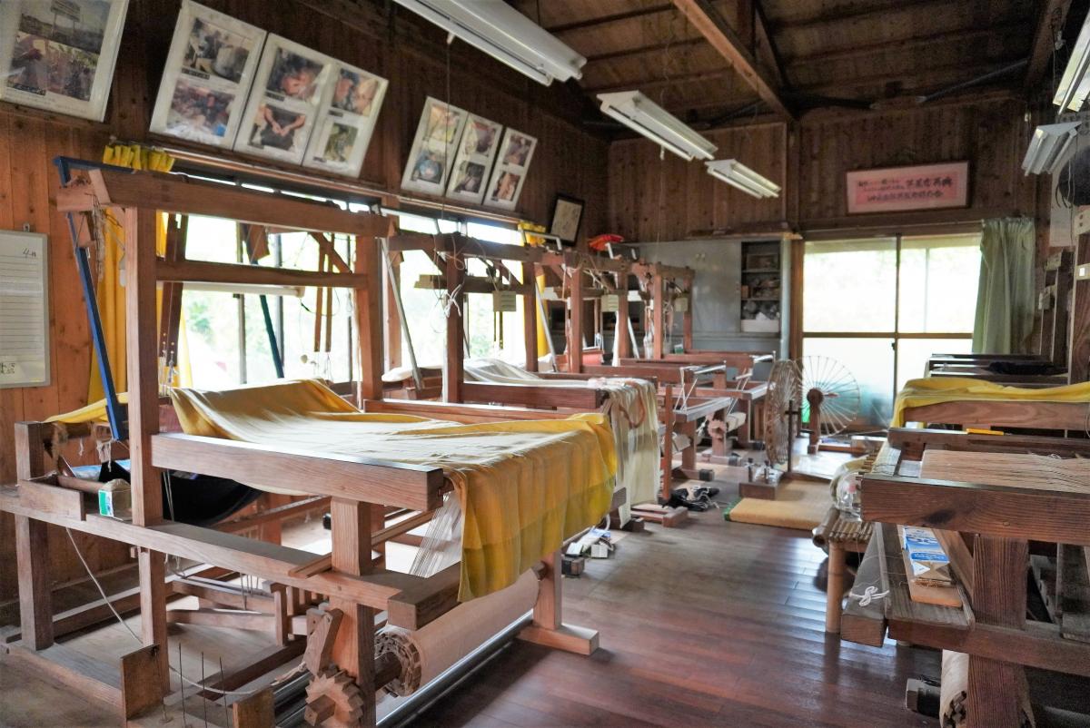 沖永良部芭蕉布会館の建物の中で、木製の機織りが数台並んでいる体験場の写真