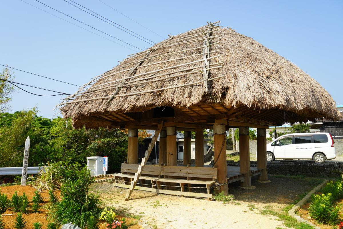 萱葺きの大きな屋根を9本の木製の柱が支えている高倉の写真