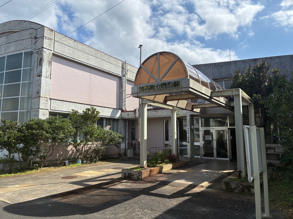 青空の下でルーフ屋根の渡り廊下と2階建の建物がつながっている写真