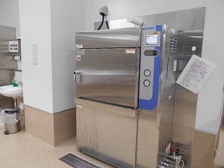 厨房の角に設置された大型のステンレス製の真空冷却機が、右側の手洗い場とともに写っている清潔感のある作業室の写真