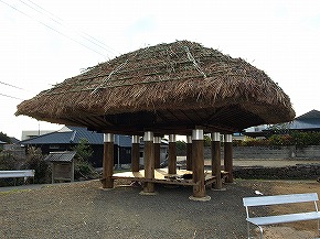 茅葺屋根で9本の太い木製の柱に支えられた九本柱の高倉の写真