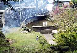 アーチ状のコンクリートの壁に階段が続き手前には芝生が広がった側に川があるジッキョヌホーの写真