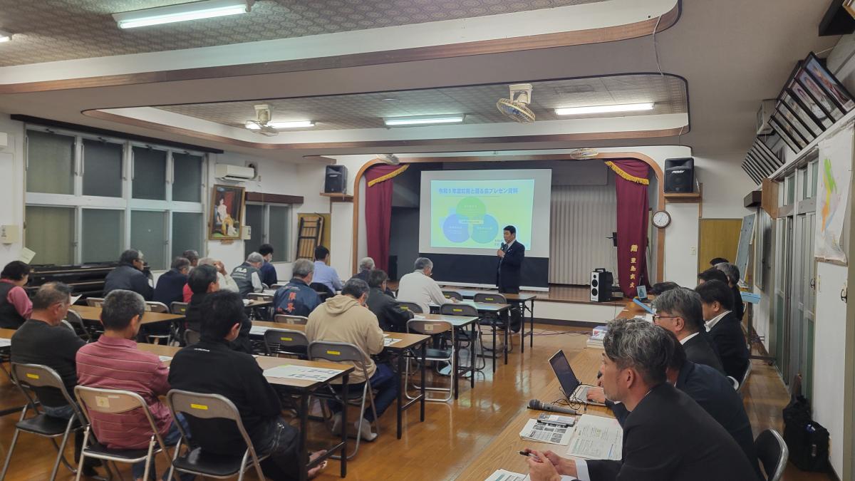 広々とした室内で、スーツ姿の男性が参加者に向かってスクリーンに映し出された図を説明しており、会場に集まった数十人の参加者は机に座って熱心に耳を傾けている住吉字の説明会の写真