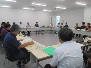 会議室で、参加者がロの字型に並べられたテーブルに着席し、資料を広げて行政部会が行われている様子を捉えた写真