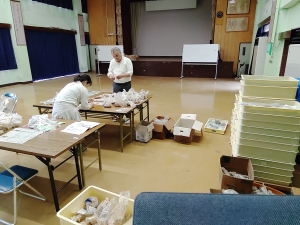 テーブルを挟んで立つ2人がテーブル上の多数の土器や石器などの遺物調査をする様子の写真