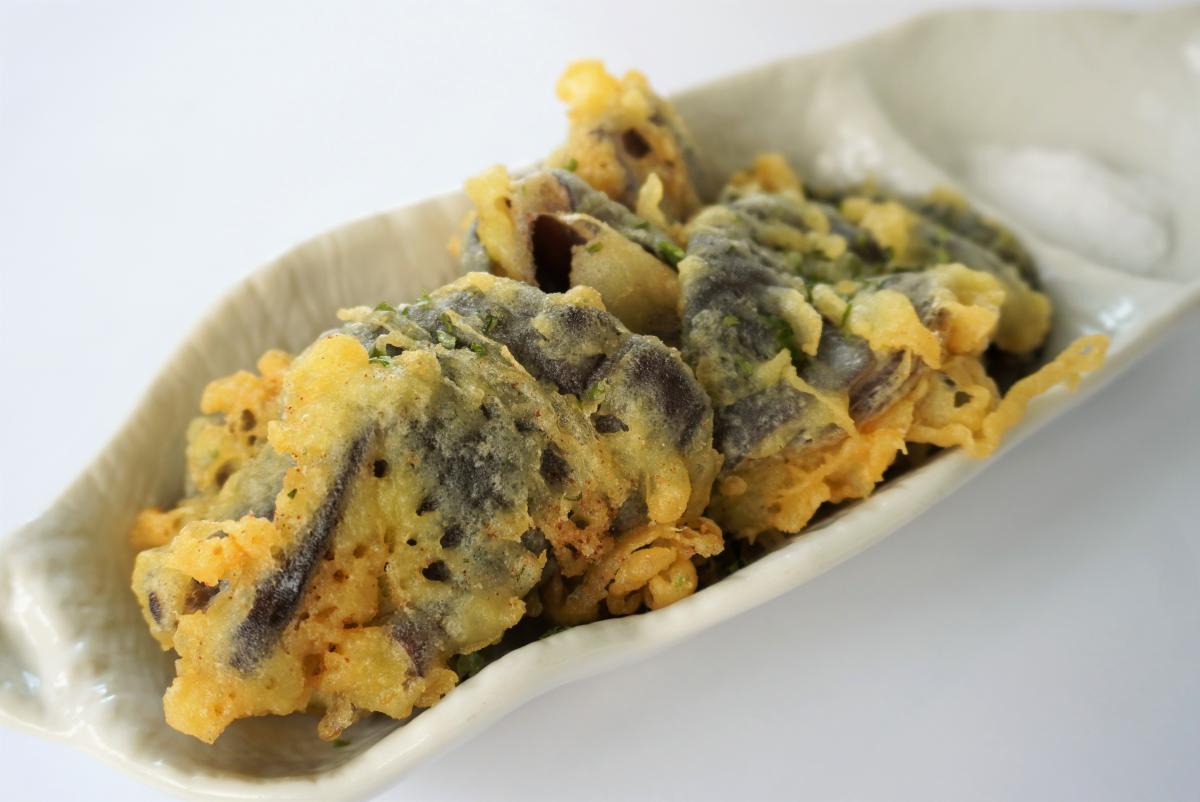 衣をまとったきくらげの天ぷらが数個、細長い白い皿に盛り付けられ、端に塩が添えられている写真