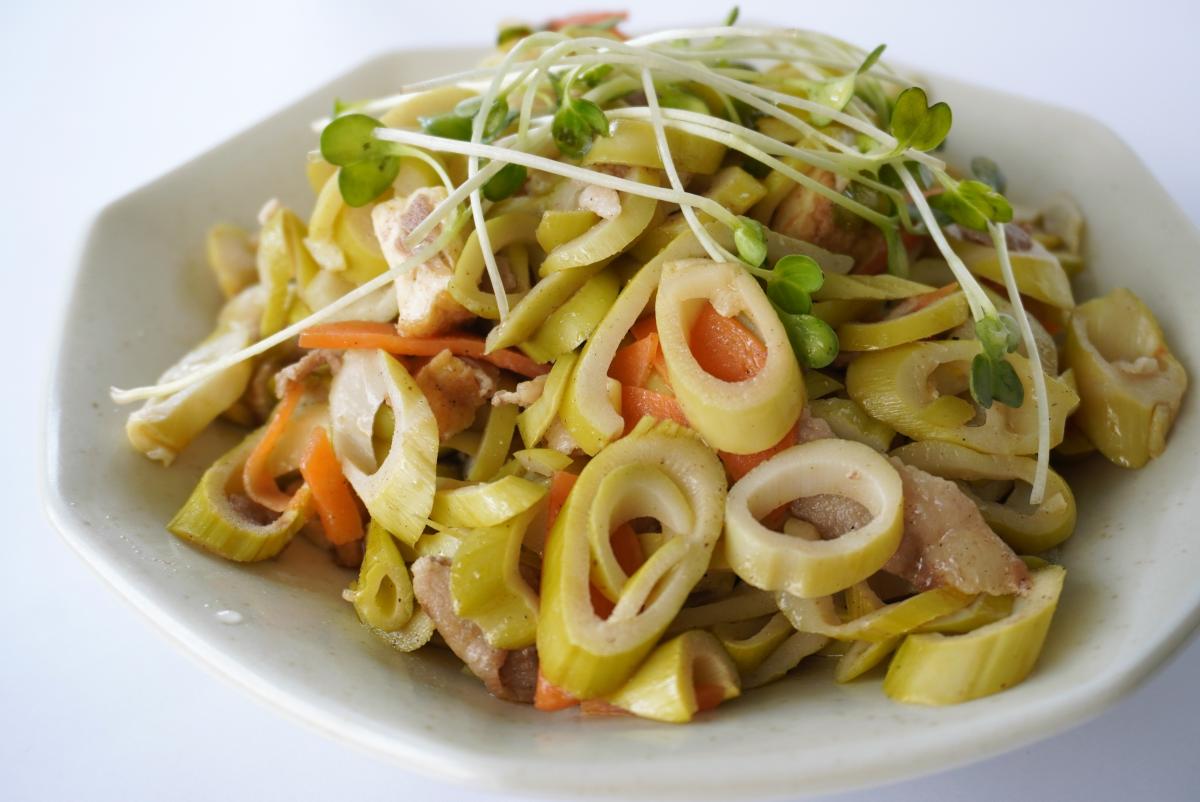 細切りのタケノコとにんじん、豚肉を炒め、上にかいわれ大根を飾った料理の写真