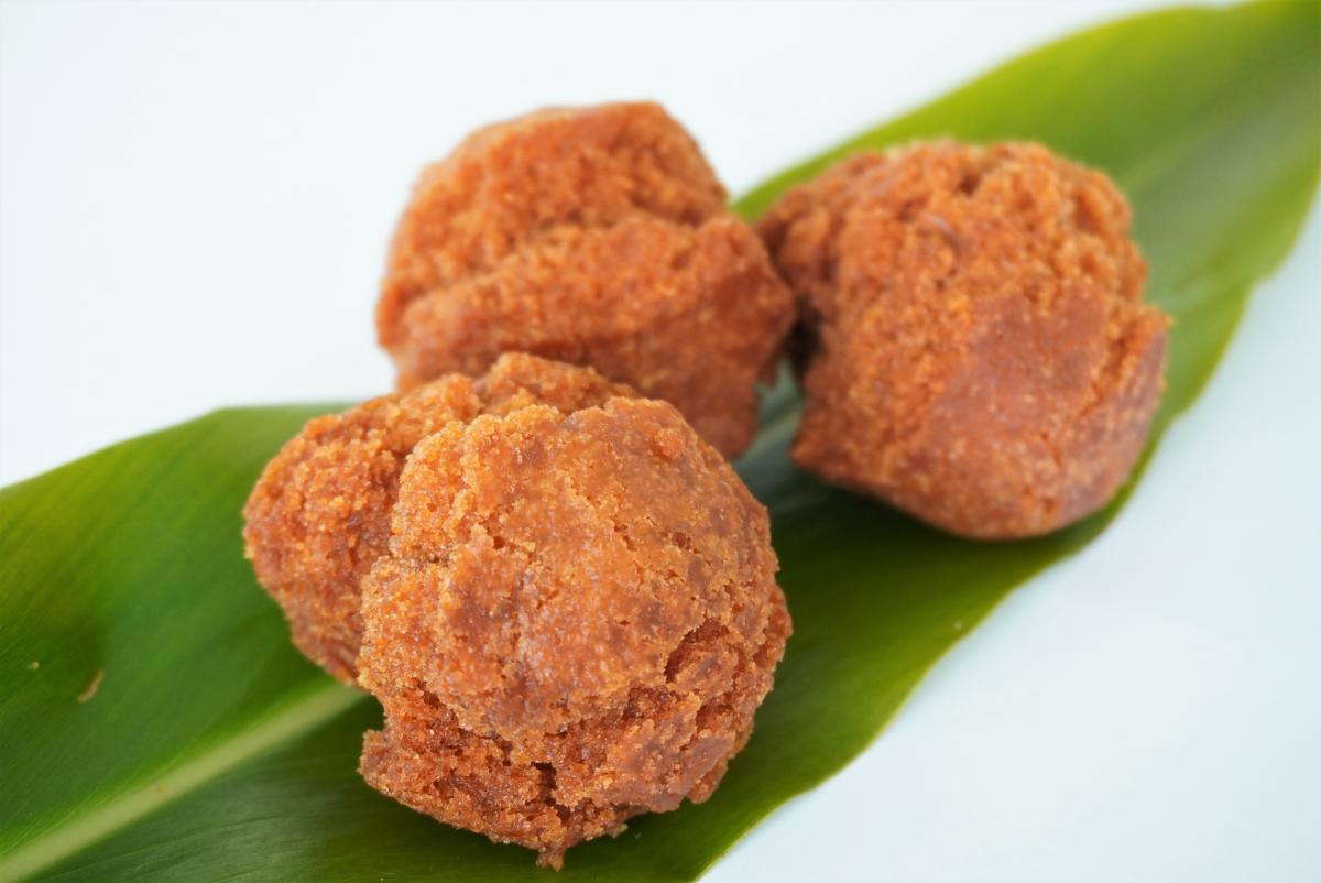 丸い揚げ菓子（サーターアンダギー）が三つ、大きな緑色の葉っぱの上に置かれた写真
