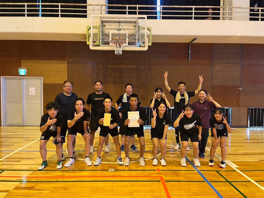 黒いユニフォームを着たメンバーが、笑顔でカメラに向かってポーズをとり、そのうち中央の2人が賞状持って笑顔で写っている集合写真