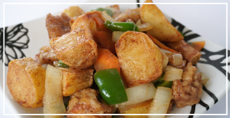 角切りのじゃがいもと鶏肉を中心に、緑のピーマンや玉ねぎ、にんじんを炒めたジャガイモ料理の写真